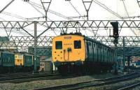 A Hadfield train leaving Guide Bridge in 1981. On the left stands a group of class 76 electric locomotives used on the Manchester-Sheffield-Wath <I>Woodhead</I> route.<br><br>[Ian Dinmore //1981]