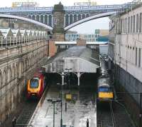 Virgin and GNER services wait in the pouring rain at the Waverley sub platforms on 9 March 2007. The recently modified walkway can be seen above the platform canopy, while through the arch of North Bridge is part of the new Edinburgh Council HQ.  <br><br>[John Furnevel 09/03/2007]