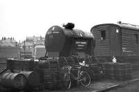 Tales of old Ferryhill 3. The wagon mounted tank looks like the waste oil container. Several oil drums and barrows for transporting them around the shed can also be seen. The converted Gresley teak bodied coach forms part of the Ferryhill breakdown train, C. 1973.<br><br>[John McIntyre /01/1973]