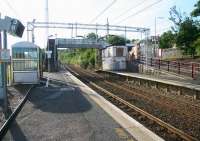 View across the platforms at Woodhall station early on a Sunday morning in July 2007. Outside the station entrance on Glasgow Road a solitary passenger can be seen utilising the interchange facilities (formerly <I>waiting for a bus</I>).<br><br>[John Furnevel 29/07/2007]