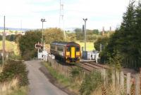 A Motherwell - Cumbernauld service runs over Heatherbell level crossing on 25 September 2007 on its way from Gartsherrie South to Garnqueen North Junction. In the right background stand chimneys of the former Gartliston fireclay works, whose products once lined many a blast furnace in the Coatbridge area and beyond.<br><br>[John Furnevel 25/09/2007]