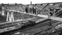 Mystery picture...thanks to all who responded to the request to help identify the old photograph - in particular to Bill Roberton who finally nailed it. The picture was in fact taken looking north across the lines outside Princes Street station, Edinburgh in 1963. Amongst the features still standing are the tenements in the right background which form the rear of Rutland Square and the tower on the skyline, which is part of St Georges West church on Shandwick Place. I have emailed details to Alex Dyne who is paying a visit to Edinburgh next week and who had requested help in identifying the location - an old family photograph of his late father who not only appears in the picture but was also the engineer who designed the bridge on behalf of the SSEB - Ed. (Old family photograph).<br><br>[Alex Dyne Collection 28/04/1963]