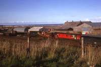 Unidentified class 26 heads the rescue train from Aberdeen Ferryhill in Fraserburgh goods yard on a late summers evening in July 1975. Loco 24118, which had derailed earlier in the day, awaits attention.<br><br>[John Williamson 09/07/1975]