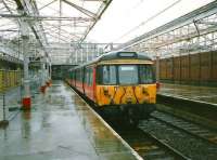 Platform 1 at Helensburgh Central in July 1997 with the canopy glazing removed and a miserable looking 303 001 standing in the rain.<br><br>[David Panton /07/1997]
