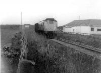 A class 24 with a very light load on the Saturday goods from Fraserburgh to Aberdeen Craiginches, passes the 18th green at Fraserburgh Golf Club in the summer of 1971. Almost all of this view has now disappeared. The St Combs road over-bridge was demolished more than 15 years ago, and the golf club-house itself has been re-built after a recent fire.<br><br>[John Williamson //1971]