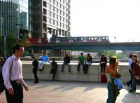 A city bound train on the Docklands Light Railway emerges from the office blocks surrounding Heron Quays station in July 2005, running out onto the bridge over the old East India Dock as it heads for Canary Wharf.<br><br>[John Furnevel 22/07/2005]