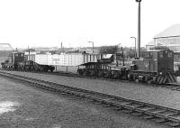 Scene at Rosyth Dockyard in the 1980s. Two Planet 0-4-0 diesel mechanical locomotives sandwich a curious-looking beam (?) wagon built by Head Wrightson, with a pair of 6-wheel bogies at each end. Presumed internal user. [Additional from Keith Falconer - this could be a nuclear submarine hot core carrier - the fuel rods for a sub would be in a round vessel which fitted a recess in the centre of the wagon. If on the main line it would normally be escorted by an armed guard in a converted mk1 coach.]<br><br>[Bill Roberton //]