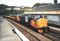 Loadhaul and EWS liveried class 37s haul an up ballast train through North Queensferry in July 1999 with the station in the process of being repainted.<br><br>[David Panton /07/1999]