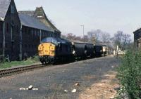 A train of loaded grain wagons approaches Dereham station in April 1984 after a trip up to the granary at North Elmham. The crew had 6 hours on the branch to conduct their brief business, a secluded rest room on Dereham station and suspicion for inquisitive strangers with cameras. Photographing this train on the move north of Dereham became a game of endurance and disinformation. This traffic ceased in 1989 and the line is fortunately now in the hands of the Mid Norfolk Railway.<br><br>[Mark Dufton 27/04/1984]