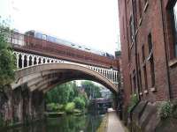 A Northern 156 crosses the Bridgewater Canal heading west from Deansgate to Castlefield Junction. The impressive girders on the skewed bridge structure can be seen as can Deansgate canal tunnel beyond. After crossing this bridge the train will pass under the former CLC lines that now carry the Manchester Metrolink trams. <br><br>[Mark Bartlett 07/07/2008]