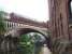 A Northern 156 crosses the Bridgewater Canal heading west from Deansgate to Castlefield Junction. The impressive girders on the skewed bridge structure can be seen as can Deansgate canal tunnel beyond. After crossing this bridge the train will pass under the former CLC lines that now carry the Manchester Metrolink trams. <br><br>[Mark Bartlett 07/07/2008]