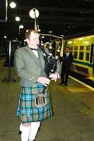A piper welcomes First ScotRail's inaugural service - a train for Gourock about to leave Glasgow Central on 17 October 2004.<br><br>[Ewan Crawford 17/10/2004]