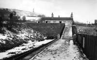 <I>That ramp looks treacherous.</I> A clear but cold day at Holcombe Brook terminus shows the small station building, at the top of a steep ramp, sitting at right angles to the track and behind, on Holcombe Hill, the 128 feet high Peel Tower. This was built in memory of Sir Robert Peel, founder of the Metropolitan Police, who was a son of Bury. Opened in 1852 the tower is still a local landmark. [See image 23868] for a modern day comparison of this scene.<br><br>[W A Camwell Collection (Courtesy Mark Bartlett) 03/02/1952]