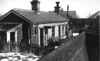 <I>Winter gricing</I>. On a cold February day in 1952, two enthusiasts wait between trains at the Holcombe Brook terminus during a visit shortly before closure. The little station building sat at right angles to the line in an elevated position overlooking the platform. The raised area now forms part of the village pub car park but the old platform and goods yard have been occupied by a small development of shops. <br><br>[W A Camwell Collection (Courtesy Mark Bartlett) 03/02/1952]