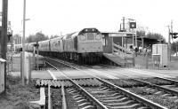 A Type 2 heading towards Carnforth and the WCML about to run over Green Road level crossing after passing through the station on 7 October 1983. The locomotive is hauling a lengthy train consisting entirely of condemned DMU stock.<br><br>[John Furnevel 07/10/1983]