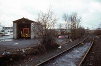 The <I>Nickey Line</I> between Hemel Hempstead and Harpenden carried traffic until 1979 when the Hemelite building block factory at the western end switched to road transport to import its raw materials. Shown here are the factory sidings at Cupid Green near Hemel Hempstead a few months before the rail traffic ceased, complete with the company's Ruston loco tucked away in its shed for the Christmas break. Appropriately, the shed is built from <I>Hemelite</I> aggregate blocks.<br><br>[Mark Dufton 26/12/1978]