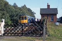 In the late 1970s, the former Midland and Great Northern station at Lenwade had a regular passenger service, albeit one visit a year from a succession of special excursions. This is the 1978 trip, in the form of a Birmingham/Cravens DMU chartered by the Aylsham and District Railway Action Committee. Despite the heroic local efforts, the line from Lenwade to Wroxham was closed and dismantled in the early 1980s. The station building survives, sensitively restored as a private family house.<br><br>[Mark Dufton 16/09/1978]