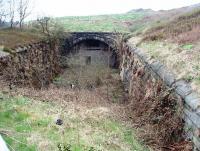 The south end of Newline tunnel on the steep climb to Britannia summit. Closed to regular traffic in 1947 the tunnel is now a vehicle workshop, accessed from the north side although there appears to be a fire escape door in this bricked up south portal.  Viewed from the A6066 Stacksteads to Bacup road at SD 877216 the buildings on the horizon overlook the north portal showing how shallow the land over the tunnel roof is. [See image 35969]<br><br>[Mark Bartlett 16/04/2009]