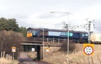 A container train, hauled by DRS 66412, crosses Lampits Road on the approach to Carstairs station on the ex-Caledonian route from Edinburgh in March 2007. The train has travelled via the ECML and the <I>sub</I> and has just over 30 miles still to go on its journey to WHM, Grangemouth. <br><br>[John Furnevel 08/03/2007]