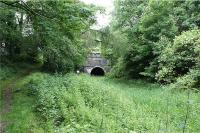 The east end of Hincaster tunnel under the WCML (which can just be made out above the tunnel entrance). Although this looks like a single track railway tunnel, it is in fact part of the abandoned Lancaster Canal which formerly operated between Preston and Kendal. The tunnel was constructed during 1816 & 1817 and is 378 yards long. Over 4 million bricks were used in the construction of the tunnel and in its day was the first major brick structure north of the River Mersey. The path to the left also leads under the WCML, over the hill and to the west side of the tunnel. It was used by the horses that pulled the barges on the canal as there was no towpath through the tunnel. The last commercial traffic passed through the tunnel in 1944. See also photos 21298 and 21302. This is a key point on yesterdays and todays transport networks as the A590 dual carriageway also passes under the WCML approx 50 yards to the right of the picture.<br><br>[John McIntyre 20/06/2009]