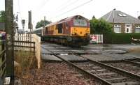 EWS 67011 westbound over Kingsknowe level crossing on a wet Saturday morning heading for Polmadie with the empty stock of the Edinburgh portion of the Lowland Sleeper.<br><br>[John Furnevel 18/07/2009]