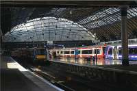 Sunshine breaks into the train shed at Glasgow Queen Street and illuminates SPT and First ScotRail liveried Turbostars on platform 5 on 25 July 2009. Another Turbostar hides in the shadows on platform 6.<br><br>[John McIntyre 25/07/2009]