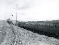 A Leeds - Glasgow train heads north at Lugton behind a <I>Peak</I> in March 1966. The locomotive is about to pass between the abutments of the overbridge that once carried the Lanarkshire and Ayrshire Railway over the formation at this point.<br><br>[Colin Miller /03/1966]