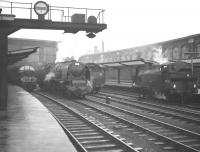 Scene at the south end of a rain soaked Carlisle station on 28 December 1963. From left to right are D323 with a Glasgow - Liverpool train, 46240 <I>City of Coventry</I>, the tender of 46225 <I>Duchess of Gloucester</I> and 47326, the station pilot.<br><br>[Robin Barbour Collection (Courtesy Bruce McCartney) 28/12/1963]