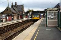 142004 calls at Burscough Bridge on 15 October 2009 whilst on it's way to the seaside at Southport. The substantial station building on the Wigan platform is currently up for sale. Behind the bus shelter on the right is the excellent Burscough Bridge Interchange building for both bus and rail services.<br><br>[John McIntyre 15/10/2009]