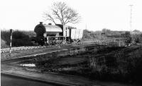 A NCB Austerity 0-6-0ST leaves the colliery yard, and approaches the 'B' road level crossing, with a single wooden bodied coal wagon in tow. Although most of the wagons seen around the pit that day in 1975 were standard unfitted 20T steel hoppers there were still a large number of these wooden bodied trucks in internal use, even at this late date. <br><br>[Mark Bartlett //1975]