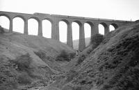 A <I>Peak</I> takes a northbound train across the 11 arches of Arten Gill Viaduct in the 1960s. The imposing structure was built using the distinctive locally obtained dark limestone which was referred to as <I>Dent marble</I> after polishing.<br>
<br><br>[Robin Barbour Collection (Courtesy Bruce McCartney) //]