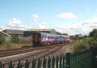 A Morecambe to Lancaster service passes the junction for Heysham seen from the adjacent cycle track. Just to the left of Sprinter 156454, between the two modern buildings, the old goods shed from the LNWR station at Morecambe Euston Road can be seen, still in use by a local builders' merchant. <br><br>[Mark Bartlett 13/08/2009]