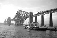 Scene at Hawes Pier, South Queensferry in June 1962 as the paddle-driven ferry <I>Robert the Bruce</I>, (with a carrying capacity of 28 cars), prepares for another crossing. One of 4 such ferries withdrawn on the opening of the road bridge in 1964, it was cut up by P&W McLellan at Bo'ness the following year.  Meantime, high above the water, a Standard Class 5 and a B1 can be seen double-heading a northbound goods train onto the Forth Bridge.<br><br>[Frank Spaven Collection (Courtesy David Spaven) /06/1962]