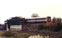 An early evening Up train from the south coast to London Waterloo, formed by express EMU 2416, crosses Battledown Flyover just to the west of Basingstoke. The Salisbury lines pass under the flyover while the Down line to Winchester and Southampton goes off to the left.<br><br>[Mark Bartlett 24/04/1991]