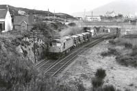 26013 departs Kyle with Presflos for the Howard Doris oil rig yard at Stromeferry in 1977.  The former locomotive shed was located on the right.<br><br>[Bill Roberton //1977]