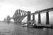 Scene at Hawes Pier, South Queensferry in June 1962 as the paddle-driven ferry <I>Robert the Bruce</I>, (with a carrying capacity of 28 cars), prepares for another crossing. One of 4 such ferries withdrawn on the opening of the road bridge in 1964, it was cut up by P&W McLellan at Bo'ness the following year.  Meantime, high above the water, a Standard Class 5 and a B1 can be seen double-heading a northbound goods train onto the Forth Bridge.<br><br>[Frank Spaven Collection (Courtesy David Spaven) /06/1962]