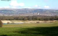 A panoramic shot looking east over the town of Horwich on a chilly 2 March 2010, with the appropriately named Winter Hill in the background. The former railway works stretches across the centre of the frame as the top of a First TransPennine train is seen running past in the foreground on the line from Bolton to Chorley and Preston. Opened by the L&Y in 1886 the works employed over 5,000 people at it's peak. Horwich produced its last new locomotive in 1957 and completed its last overhaul in 1964. The works continued to be used for general rolling stock into the 1980s but was eventually sold by BREL in 1988. The former works is now part of a large industrial estate named 'Horwich Loco' with most of the buildings still being put to good use.<br>
<br><br>[John McIntyre 02/03/2010]