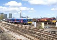 Scene at Didcot on 8 April 2010 as a Paddington bound First Great Western 165 DMU coming off the Oxford line passes 66024 on a freight.<br><br>[Peter Todd 08/04/2010]
