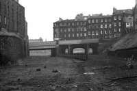 Looking east along the Caledonian trackbed towards the site of Princes Street station in 1972, with the tenements of Gardners Crescent straight ahead. The old station had by then been demolished, giving a view of the rear of the Caledonian Hotel in the left background. To the right was the route into the original Lothian Road station, latterly a goods depot. The area has seen considerable change over the years, although the bridge on the left still stands, albeit now spanning Edinburgh's Western Approach Road. [See image 31813 for the view west from the other side of the bridges at this time.]<br>
<br><br>[Bill Jamieson //1972]