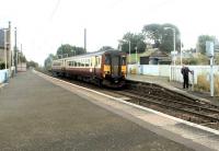 Platform scene at Kirknewton in September 2002. The driver of an Edinburgh - Glasgow Central stopping train is manually activating the half-barrier level crossing before leaving the station.<br><br>[John Furnevel 03/09/2002]