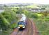 Train on Fife outer circle between Inverkeithing East junction and Inverkeithing Station in May 2005. Note the 66 with a Coal train being loaded by JCB on the west curve sidings in the background.<br><br>[John Furnevel /05/2005]