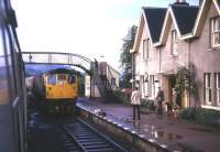 Trains crossing at Strathcarron station following a shower of rain in the summer of 1974. Approaching the camera is a Class 26 hauled service from Kyle of Lochalsh bound for Inverness.<br><br>[David Spaven //1974]