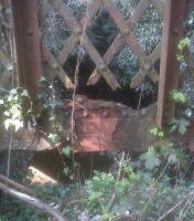 The lattice fence used to stop passengers falling down the gap between the platforms, which were separate spans of an accommodation underbridge. Now you can see through the fence to the arch of the bricked-up pedestrian entrance.<br><br>[Ken Strachan 23/04/2010]