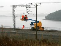 A grey day just west of Forrestfield on 12 October sees a 3-man team engaged in electrification work in connection with the Airdrie - Bathgate project. Hillend reservoir forms the backdrop with Caldercruix in the left background. <br><br>[John Furnevel 12/10/2010]