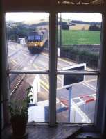 View from Insch signal box as an Inverness - Aberdeen train runs over the level crossing into the station in August 1987.<br><br>[Ian Dinmore /08/1987]
