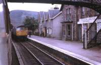 Kyle line trains, hauled by BRCW Type 2 Class 26 locos, cross at Achnasheen in the summer of 1972. View from the Kyle bound train as the driver of the Inverness working hands over the single line token.<br><br>[David Hindle //1972]