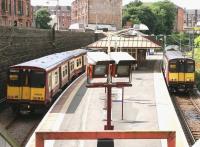 A Cathcart Circle train (L) passes a Neilston line service at Queens Park station in July 2005. View west from the Victoria Road entrance. <br><br>[John Furnevel 03/07/2005]