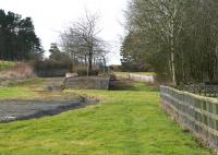 The remains of the station at Leadburn on the Peebles Railway, one time junction for the Dolphinton line. The station closed in 1955 and, following complete closure of the Peebles line in 1962, was turned into a picnic site [see image 50015]. Nowadays the site is inaccessible, secured by a padlocked gate alongside the A6094, from which this photograph was taken on 8 March 2015 looking south west towards the junction.<br><br>[John Furnevel 08/03/2015]