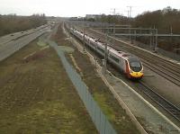 Road vs. rail: a down Pendolino forms an orderly queue for platform 6 at Milton Keynes as road traffic (more vehicles, less passengers) passes on the A5. View looks North on 4 February.<br><br>[Ken Strachan 04/02/2011]