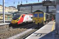 Freightliner Heavy Haul 66551 pauses at Carlisle platform 3 for a crew change on 18 March with the 4S70 Drax PS - Ayr empties, as a Euston-bound Pendolino arrives at platform 4.<br><br>[Bill Roberton 18/03/2011]